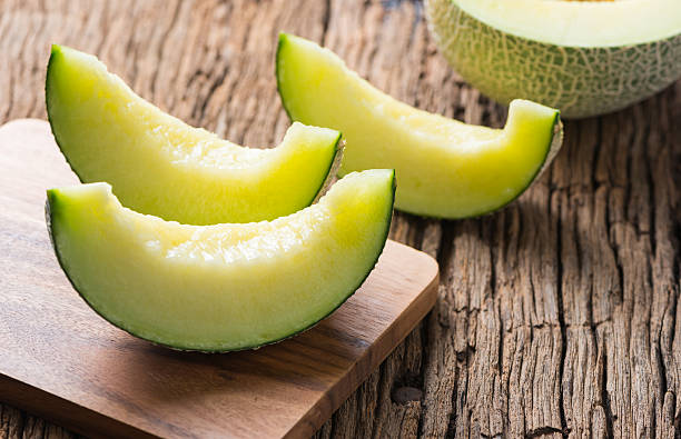 sliced japan melon on wood plate sliced japan melon on wood plate and old wood background honeydew melon stock pictures, royalty-free photos & images