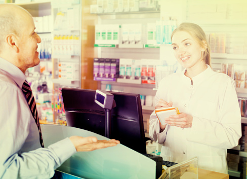 Female pharmacist staff counseling customer about drugs usage in modern farmacy