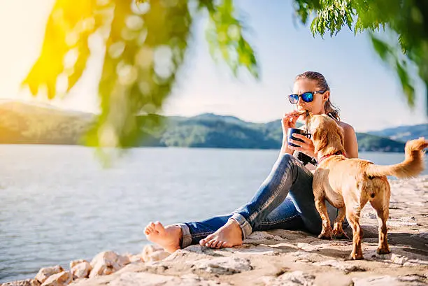 Photo of Woman and dog on a beach eating cookies