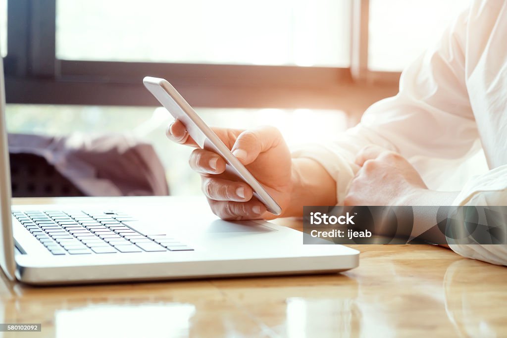 Businessman using laptop and mobile phone. Businessman using laptop and mobile phone for online communication. Banking Stock Photo