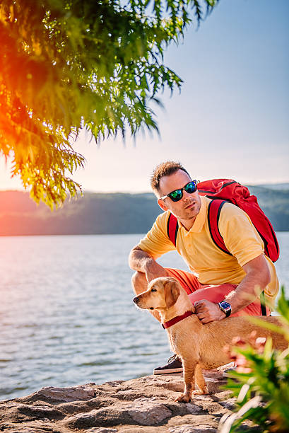 Man and dog squatting on stone dock by the sea