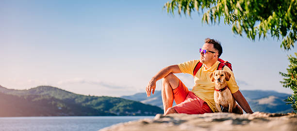 istock Man and dog sitting on a stone dock 580102458