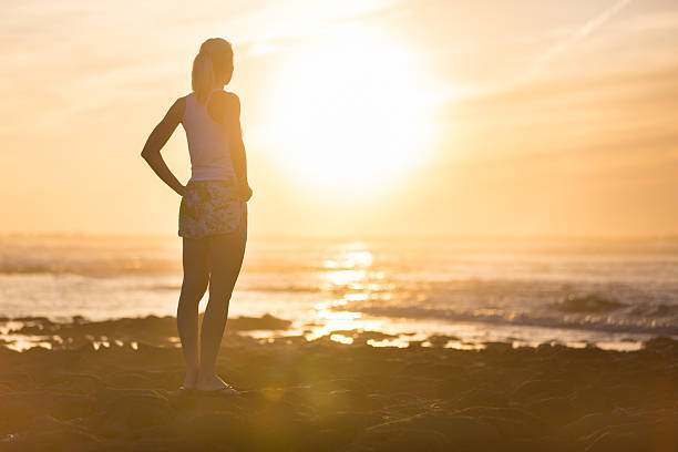 istock Woman on sandy beach watching sunset. 580103108
