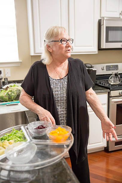 situation réelle - femme âgée distraite préparant le dîner - overweight women salad frustration photos et images de collection