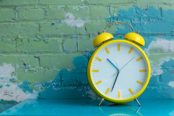 Big yellow retro style alarm clock Big yellow retro style alarm clock decorated in a living room with colorful brick wall clock face photos stock pictures, royalty-free photos & images