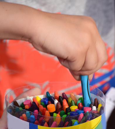 child's hand takes a blue crayon