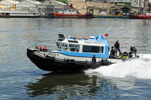 Istanbul, Turkey - June 5, 2016:  Police divers on a boat travelling rapidly up the Golden Horn, passing the Beyoglu district of Istanbul, Turkey.