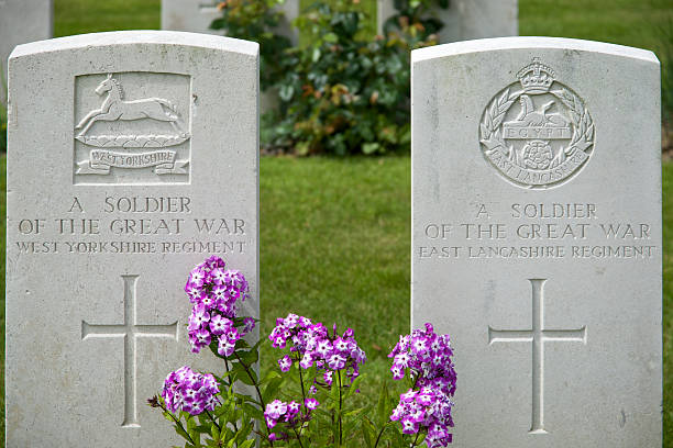 Kanchanaburi, Thailand - October 25, 2007: A female groundskeeper named Kannokan maintains the plants and beauty at Kanchanaburi War Cemetery, one of the burial places of prisoners of war who died building the Death Railway during World War II. In the foreground is the headstone of a British soldier.