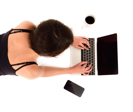 Young woman, laptop and phone. Maybe using phone to authenticate banking application