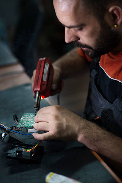 istock Repairman working in workshop and soldering electric board 580119342