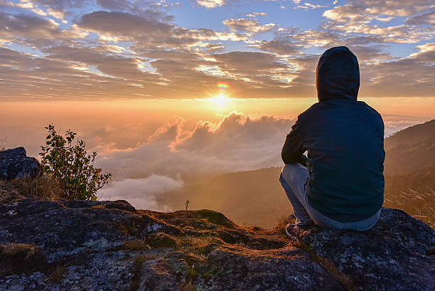 Man sitting on a mountain for watching Sunrise views. stock photo
