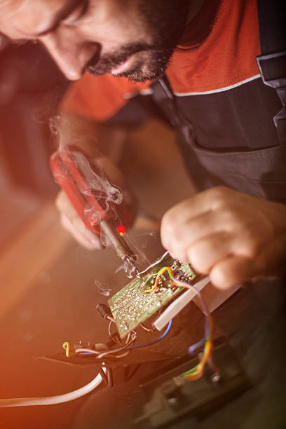 istock Repairman working in workshop and soldering electric board 580119554