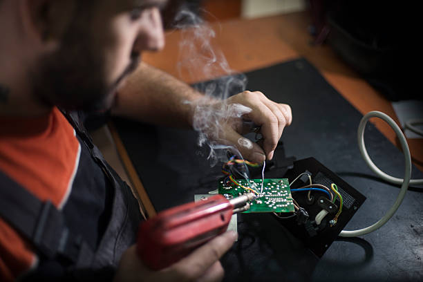 istock Repairman working in workshop and soldering electric board 580119794