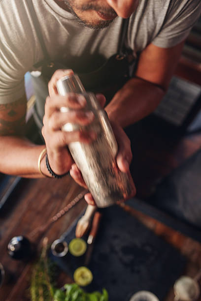 barman mélangeant une boisson dans un shaker à cocktail - shaker photos et images de collection