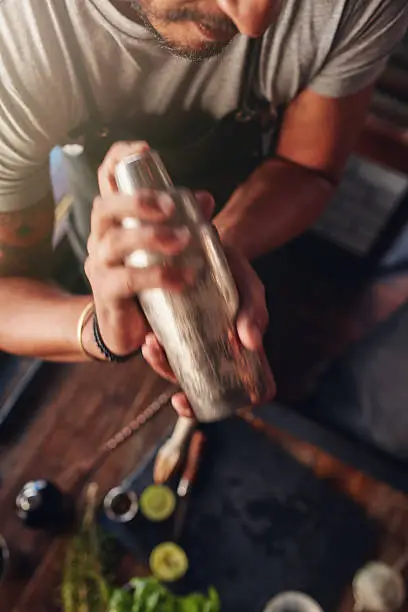 Close up shot of male bartender mixing drink in cocktail shaker