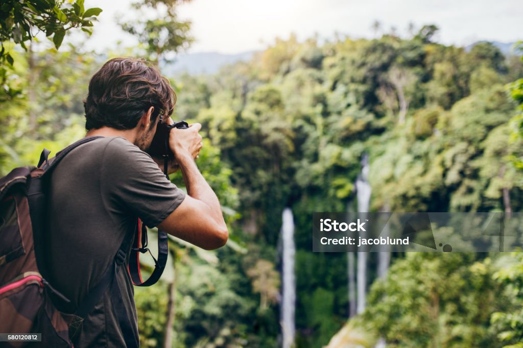 Randonneur masculin photographiant une cascade en forêt - Photo de Photographe libre de droits