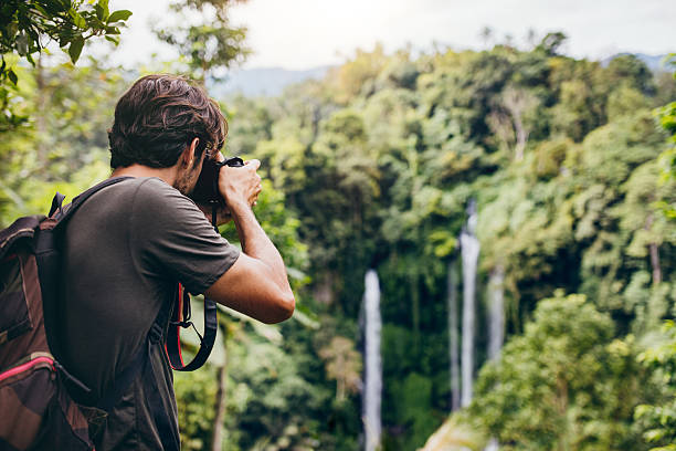 male hiker photographing a waterfall in forest - beweging fotos stockfoto's en -beelden