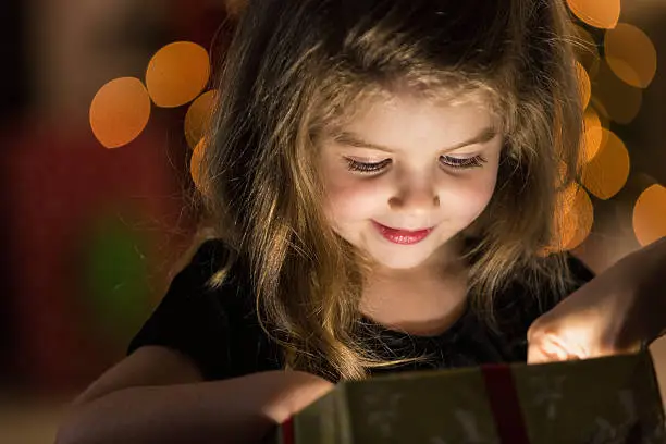 Photo of Curious girl peeks inside a Christmas present