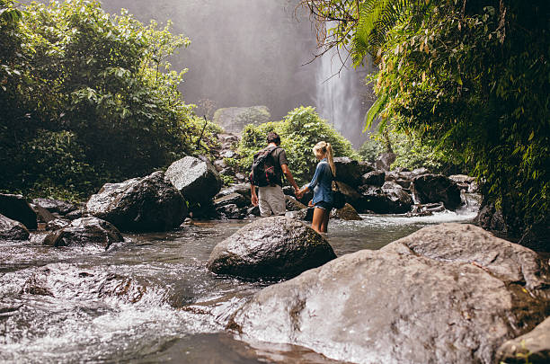 istock Young couple crossing stream in forest 580121152