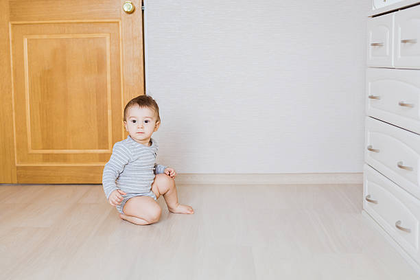 One year old cute baby boy sitting on rustic wooden floor.