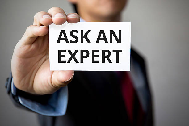 Businessman presenting 'Ask An Expert' word on white card stock photo