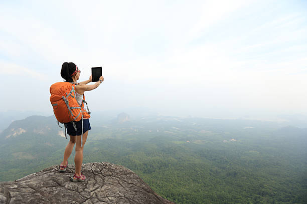 istock young woman backpacker taking photo on beautiful mountain peak 580130024