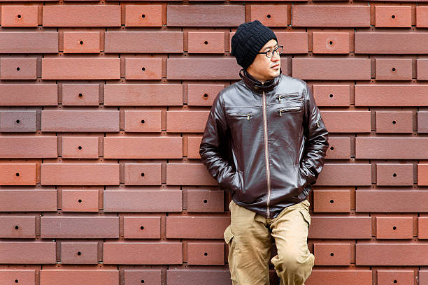 istock Asian Man in a Brown Jacket Leans Against the Wall 580130786