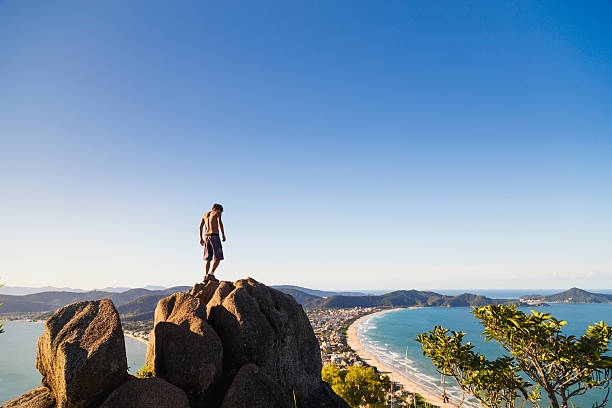 Young man on top of a mountain at Bombinhas - Santa Catarina - Brazil.