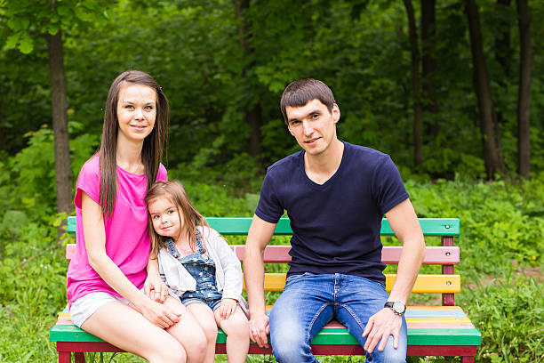 istock Family sitting on park bench 580134244