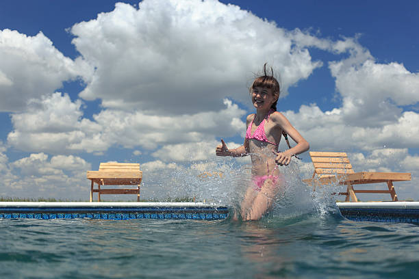 Little girl jumping in pump in an outdoor pool between fields of crops in Sicily, Italy