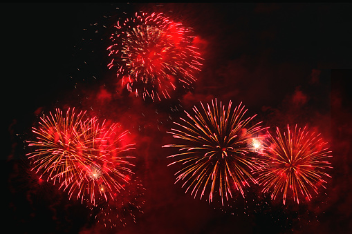 Red fireworks display in black sky background.