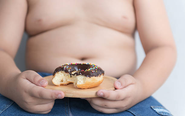 donut in hand obese fat boy. donut in hand obese fat boy on gray background, junk food can cause obesity. overweight child stock pictures, royalty-free photos & images