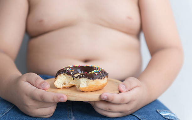 istock donut in hand obese fat boy. 582257174