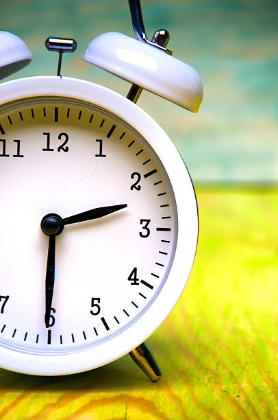 istock White alarm clock isolated on colorful wooden background 582258656