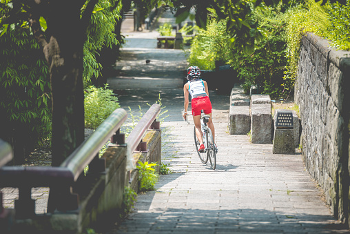 Mid adult Japanese woman riding a bike in the park of Gion in Kyoto City, Japan, Asia. Beautiful sunny day. Copy space. Rear view, full lenght. Nikon D800, full frame, XXXL. iStoskalypse Kyoto 2016.