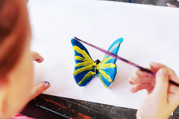 istock Girl paints a butterfly 582260696