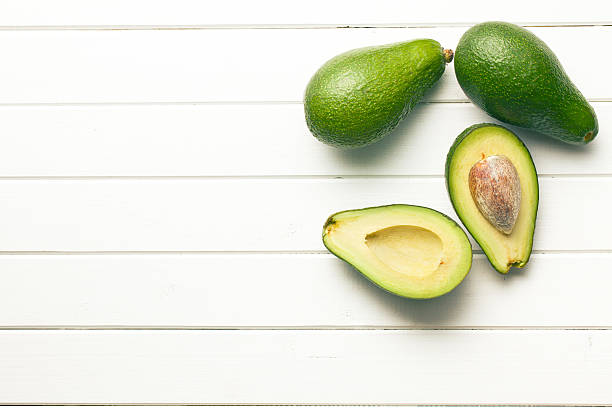 istock halved avocados on wooden background 582261226