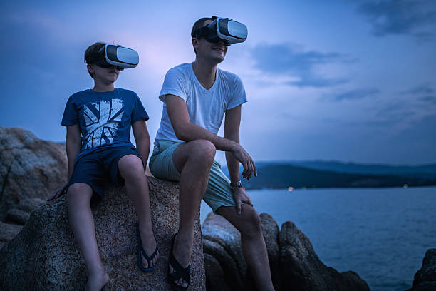 istock Father and son sitting in VR glasses outside at sunset 582263574