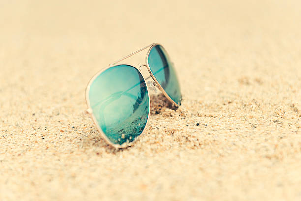 istock Reflective sunglasses in sand, reflecting the shoreline, Cornwall 582263724