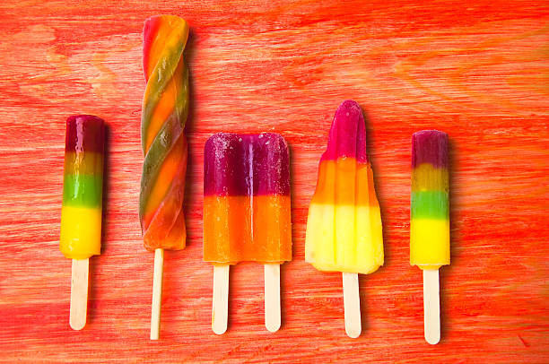 istock Colorful ice lolly on a red wooden background 582267664
