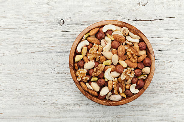 Wooden bowl with nuts. Walnut, pistachios, almonds, hazelnuts. Flat lay. stock photo