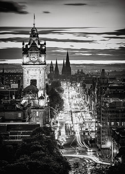 A monochrome high-angle view along Edinburgh's Princes Street at dusk.