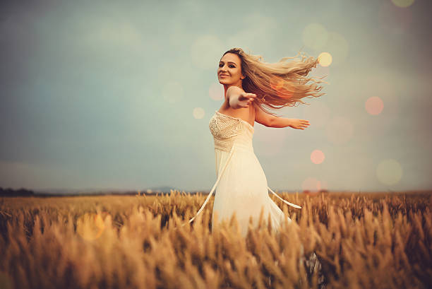 Smiling girl with long red hair stands on a green meadow on a summer sunny day.