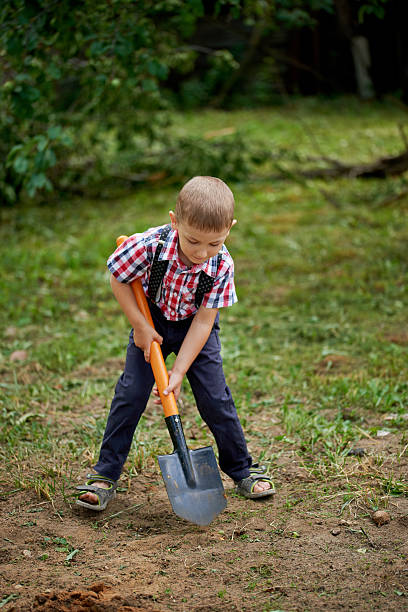 istock funny boy with shovel in garden 582286262