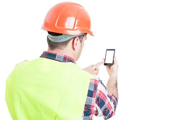 istock Backview of male engineer holding mobile phone 582287682