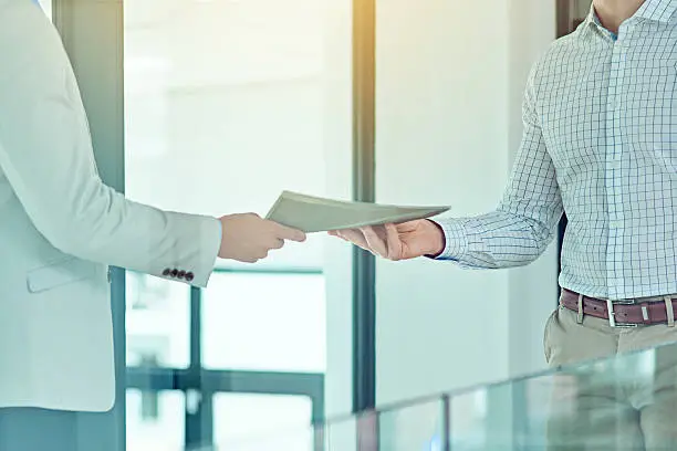 Shot of a businessman handing a document to a colleague