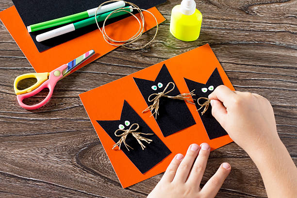 The child create a greeting card Halloween black cat out