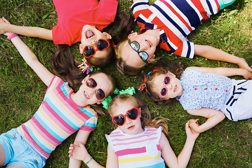 Kids in sunglasses lying on green grass