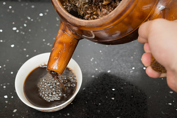 pouring herbal tea to a bowl pouring herbal tea from an enamel pot with herb to a bowl chinese herbal medicine stock pictures, royalty-free photos & images