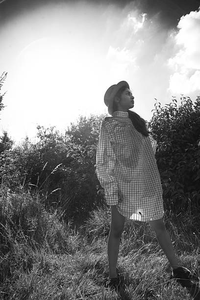 istock girl standing in nature with oversized shirt and hat 582297658